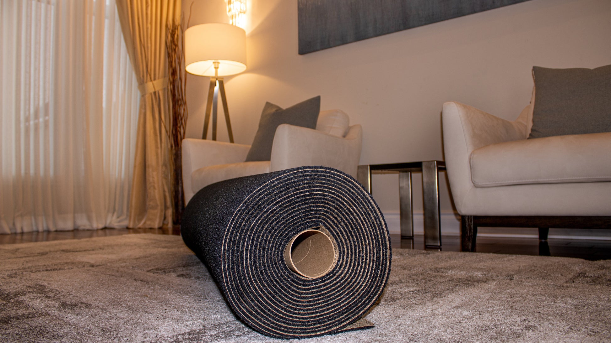 A Duralux™ Comfort 7 mm mat by Dura Undercushions rests on a high-end rug in the living room, surrounded by two chairs, a lamp, and elegant curtains.